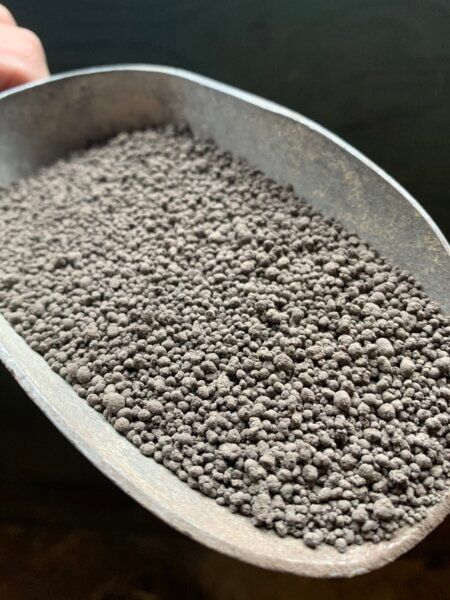 Fertoz dark grey granular in a metal scoop